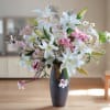 White lilies and pink orchids in a tall dark vase