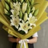 Bouquet of white lilies wrapped in bright yellow paper with a white ribbon