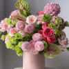 Pink and green floral arrangement in a blush vase