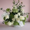 White and green floral arrangement in a pale vase
