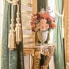 Pink and peach flower arrangement in a silver vase on an ornate table