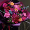 Bright bouquet of hot pink roses and carnations with yellow roses and berries wrapped in purple paper