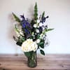 White and blue floral arrangement in a glass vase