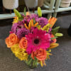 Bright mixed bouquet of pink, orange, and yellow flowers in a glass vase
