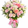 Pink and cream rose bouquet in a glass vase with a pink ribbon