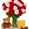 Bouquet of red and pink roses in a glass vase with a teddy bear and chocolates