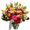 Mixed bouquet of gerbera daisies, roses, and lilies in a white vase