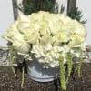 White rose arrangement in a gray container with trailing white blooms