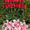 Red roses above pink-and-white lilies in a glass vase