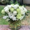 White and pale green roses arranged in a clear glass vase