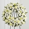 White floral wreath with lilies and roses on a black easel
