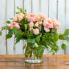 Pink roses in a clear glass vase with eucalyptus