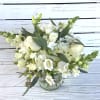 White flower arrangement with roses, hydrangea, and snapdragons in a clear glass vase