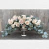 Blush roses arranged in a silver pedestal bowl with trailing eucalyptus
