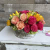 Mixed roses and sunflowers arranged in a rustic round container