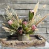 Pink protea arrangement in a wooden container with dried grasses