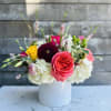 Mixed bouquet of roses, hydrangeas, and other blooms in a white vase