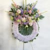 Large pastel floral wreath on an easel with pink, lavender, and green blooms