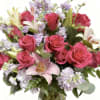 Pink roses and lilies arranged in a glass vase with lavender flowers