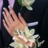 White floral corsage and boutonniere on a dark suit