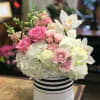 Pink and white roses with white orchids in a striped hat box