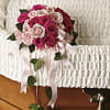 Pink and white rose bouquet with ribbon draped over a white casket