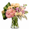 Pink and peach flowers arranged in a clear glass vase