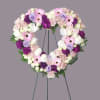 Heart-shaped floral wreath on a stand with pink, white, purple flowers