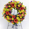 Colorful floral wreath on a metal stand with yellow, orange, purple, and pink blooms