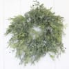 A green foliage wreath with frosted accents on a white door