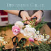 Florist arranging pink and white blooms on a worktable labeled Designer's Choice