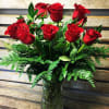 Long-stemmed red roses rise above a feathery collar of vivid green ferns
