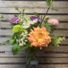 Mixed bouquet in a clear glass vase with orange, pink, and purple blooms