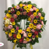 Large circular wreath of pink, yellow, and red flowers on a stand
