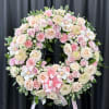 Large pink and cream floral wreath on a stand with a pink ribbon bow