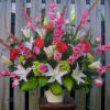 Tall bouquet of pink lilies, roses, and red gerbera daisies in a white vase