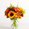 Sunflower and orange lily bouquet in a clear glass vase