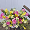Bouquet of pink roses, yellow calla lilies, and small white flowers in a white container