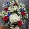 Red roses, white hydrangeas and lilies with blue accents in a white