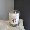 A glass candle jar with a Fig Tree label sits on a small table.