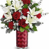 Red roses and white lilies arranged in a red glass vase