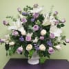 Lavender roses and white lilies arranged in a white vase