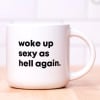 White mug with bold black text reading "woke up sexy as hell again."