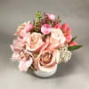 Pink and peach roses with orchids arranged in a white vase