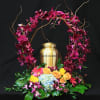 Floral urn arrangement with magenta orchids, roses, and hydrangea around a gold urn