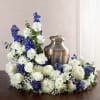 White and blue floral arrangement surrounding a metal urn