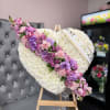 Heart-shaped floral tribute with pink and purple flowers on an easel