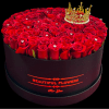 Round box of red roses topped with a gold crown