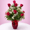 One Dz Red Roses in glass vase filled with greenery and baby