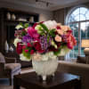 Mixed bouquet of pink, peach, white, and purple flowers in a white vase